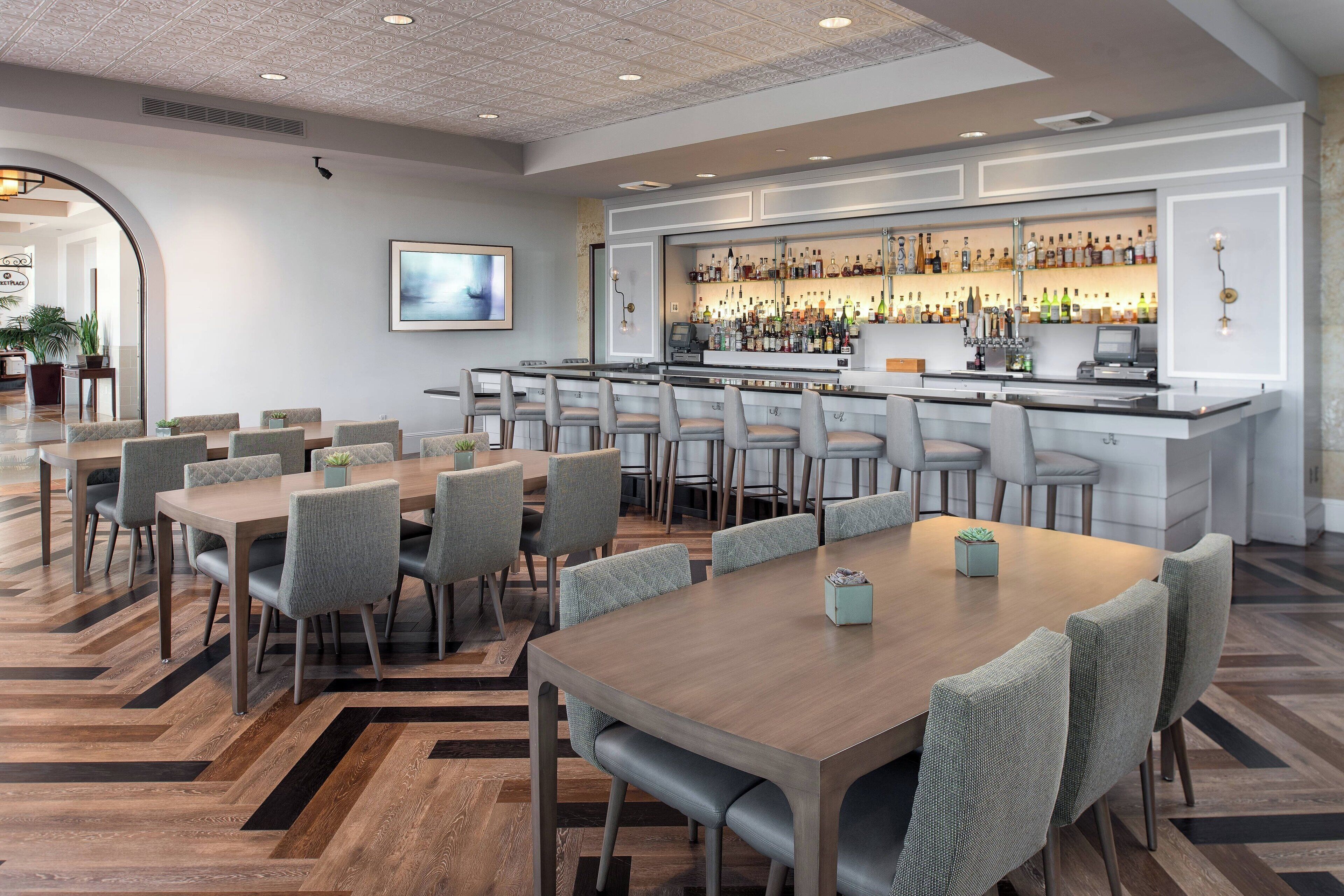En moderne hotelbar med flere siddeområder, et velassorteret barområde og et rent, moderne design.
