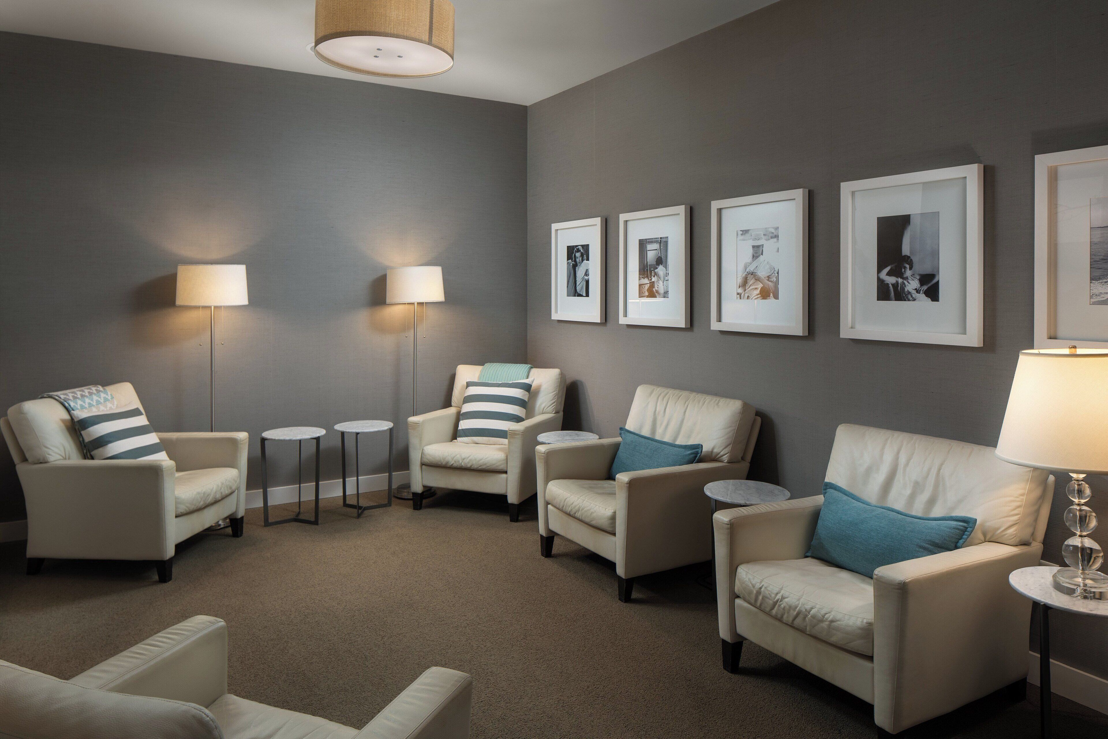 Una habitación con cuatro sillones, dos lámparas de pie y una mesita pequeña.