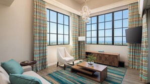 A modern living room with a sofa, armchair, coffee table, and a view of the city through large windows. - Westin Carlsbad Resort & Spa (Carlsbad)