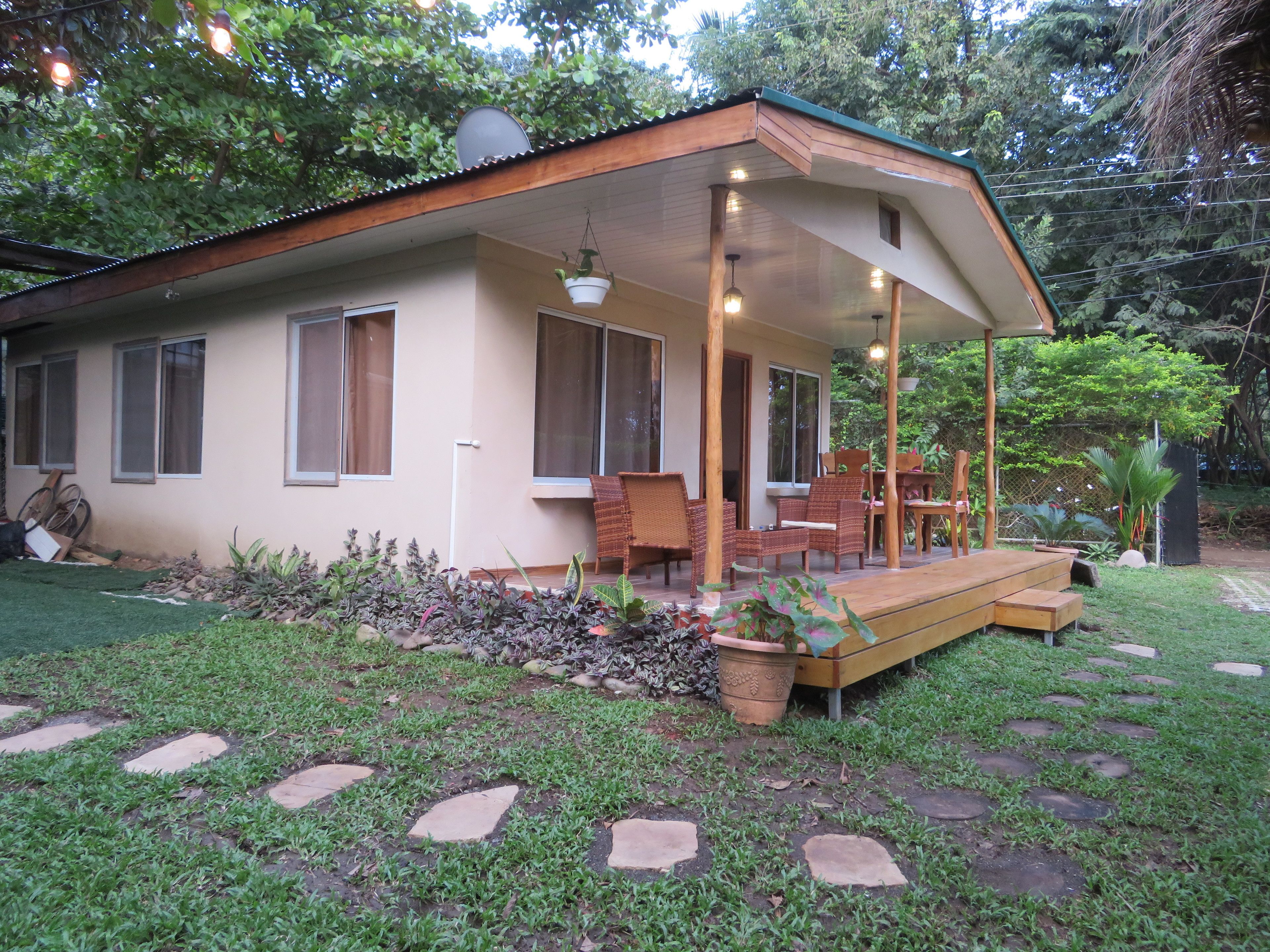 A house with a covered porch, a garden with stepping stones, and outdoor furniture.