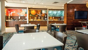 A hotel lobby with a reception desk, seating area, and a TV screen.