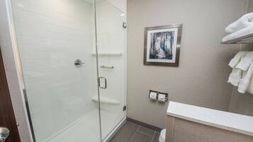 A modern bathroom with a glass shower enclosure, a toilet, and a sink area.