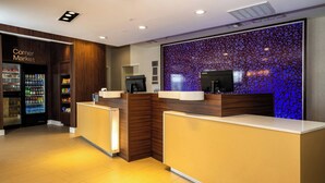 A hotel reception area with a corner market, a flat-screen TV, and a decorative wall.