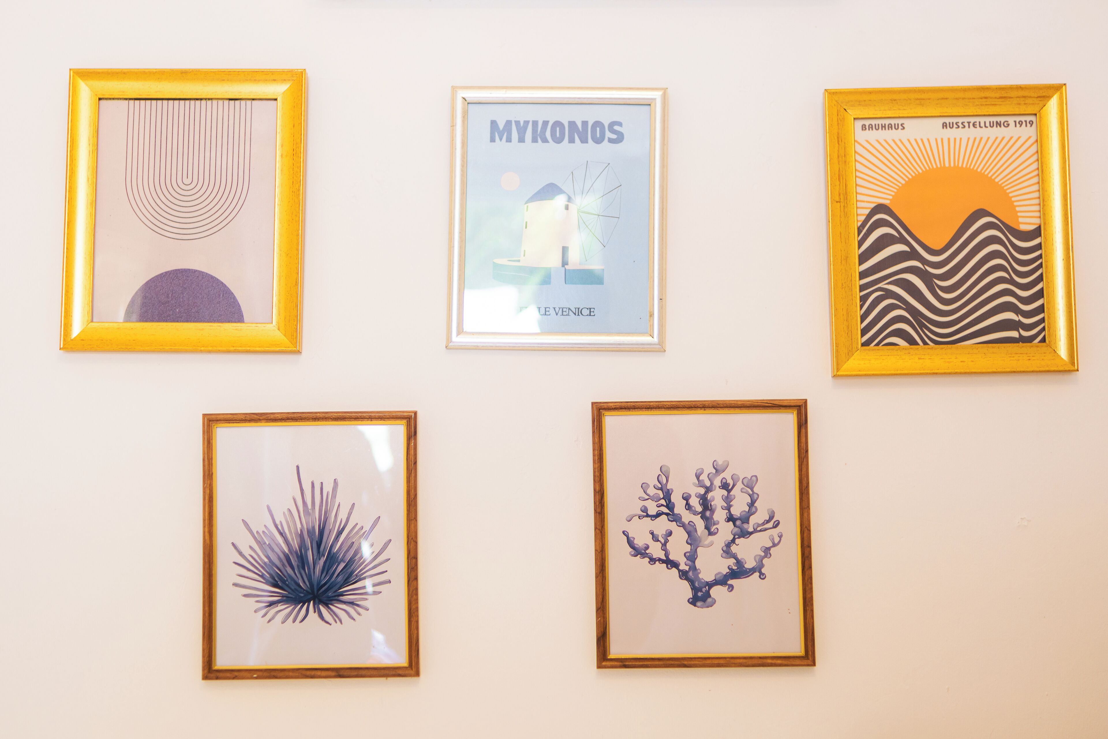 Five framed artworks on a wall.