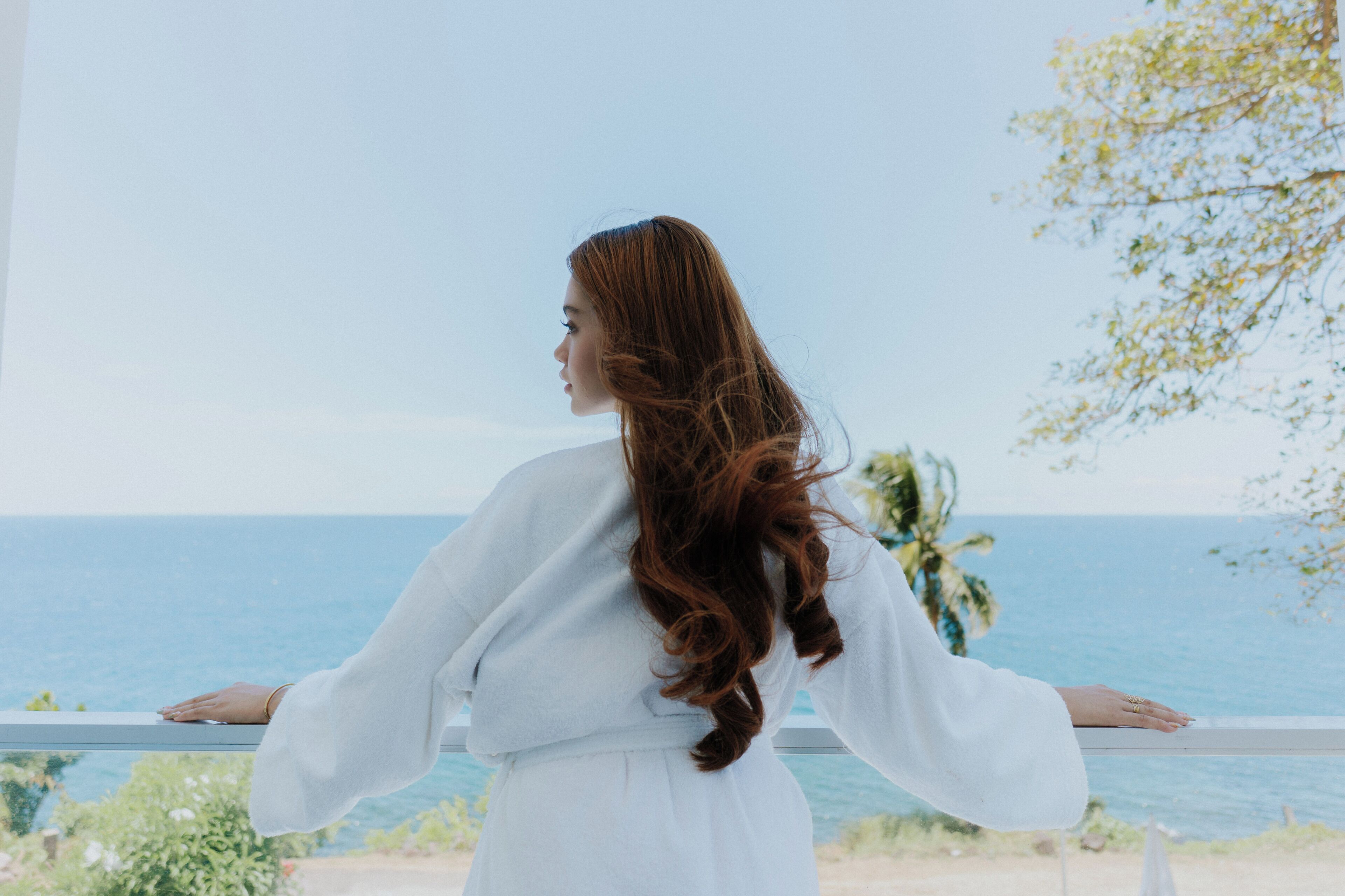 A person standing by a railing with a view of the sea.