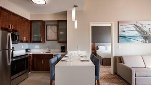 A modern kitchen with a dining area, a sofa, and a bed in the adjacent room.