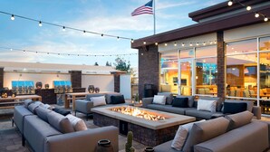 An outdoor patio with a fire pit, sofas, and string lights.