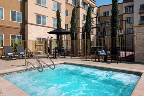 A swimming pool with lounge chairs and umbrellas, surrounded by a fence and a multi-story building with balconies. - Residence Inn by Marriott Redwood City San Carlos (San Carlos)