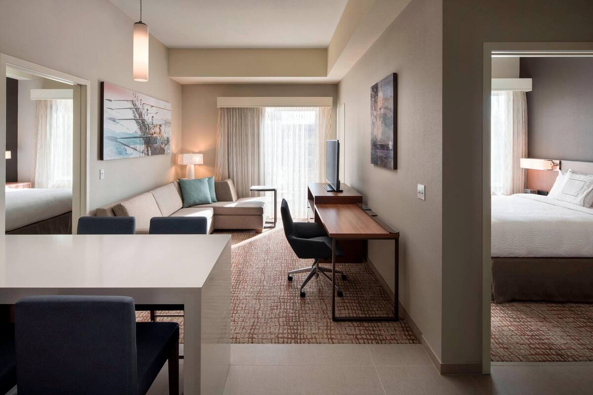 Una habitación de hotel con cama, escritorio, silla, sofá y televisión.