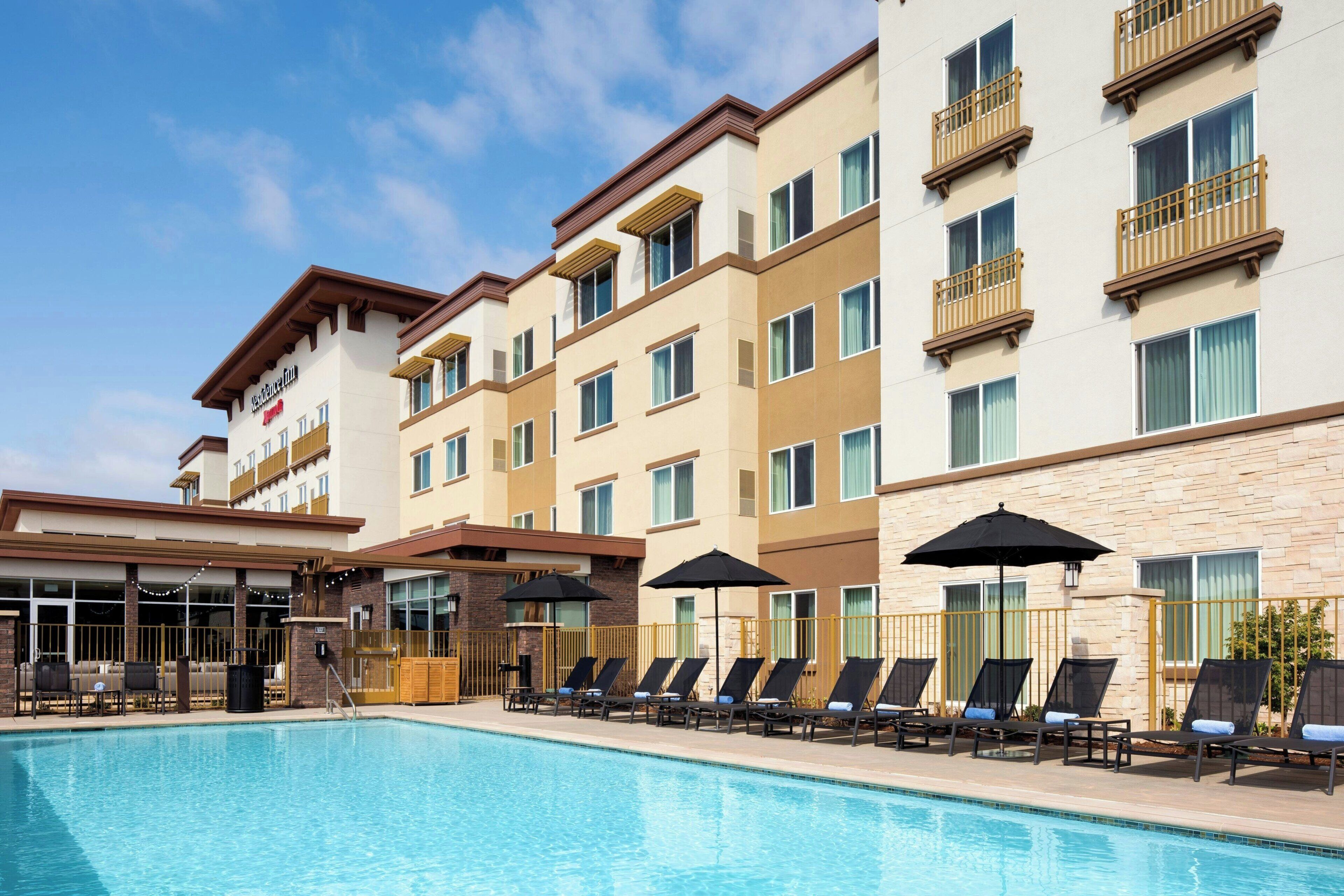 Un hotel con piscina, varios balcones y zonas de estar al aire libre.