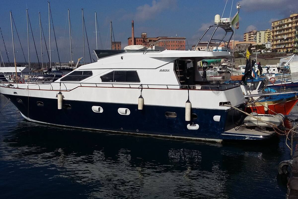 Ein Yachthafen mit einem festgemachtem Boot, das einen weißen und blauen Rumpf, eine Kabine und eine kleine Deckfläche aufweist.