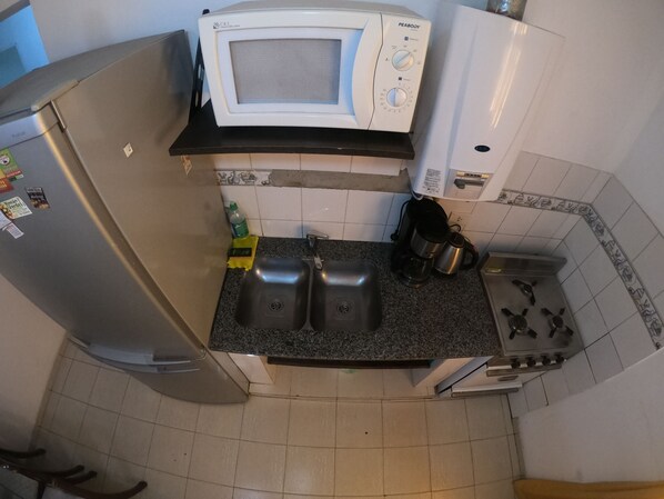 Cocina compacta equipada con refrigerador, microondas, lavaplatos y estufa.