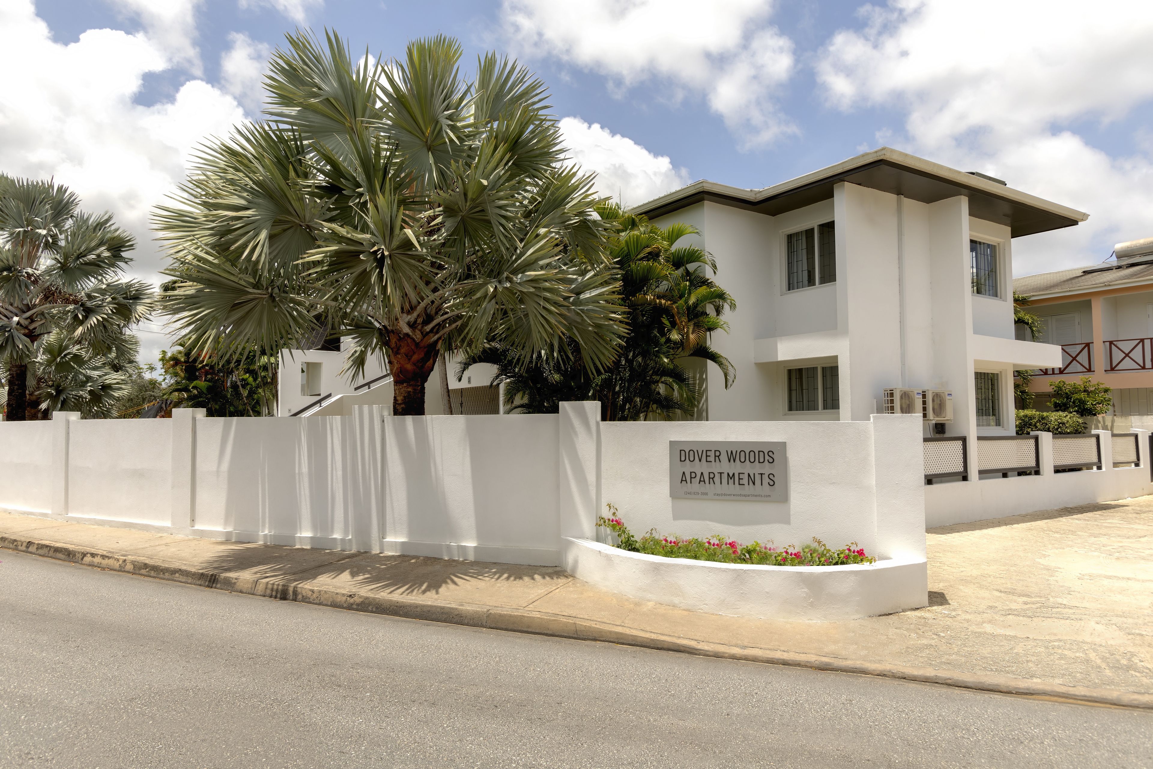 Un moderno edificio de dos pisos con fachada blanca, que dice 'Dover Woods Apartments'.