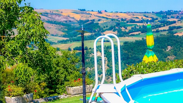Una piscina con vista libera su un paesaggio collinare.