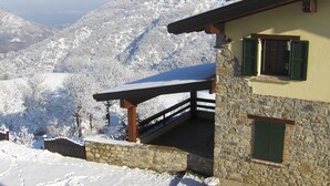 Un edificio in pietra con un balcone affacciato su un paesaggio montano innevato.
