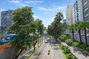Una calle urbana bordeada de palmeras y edificios modernos, bajo un cielo despejado.