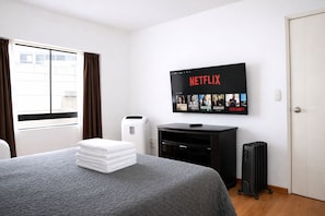 A hotel room with a bed, a TV mounted on the wall displaying Netflix, a heater, and a radiator. - Miraflores NEST Tripoli, King Bed, AC , 1000 Mb, Near Malecón & Love Park (Lima)