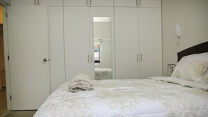 Ein Schlafzimmer mit einem großen Bett, einem Kleiderschrank und einem Spiegel.
