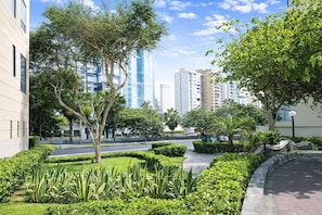 Un espace urbain aménagé, avec des bâtiments modernes, une promenade dallée et de la verdure.