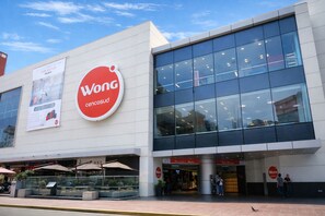 Un bâtiment moderne doté d’un grand logo rouge et blanc, d’une façade en verre et d’espaces extérieurs aménagés pour s’asseoir.