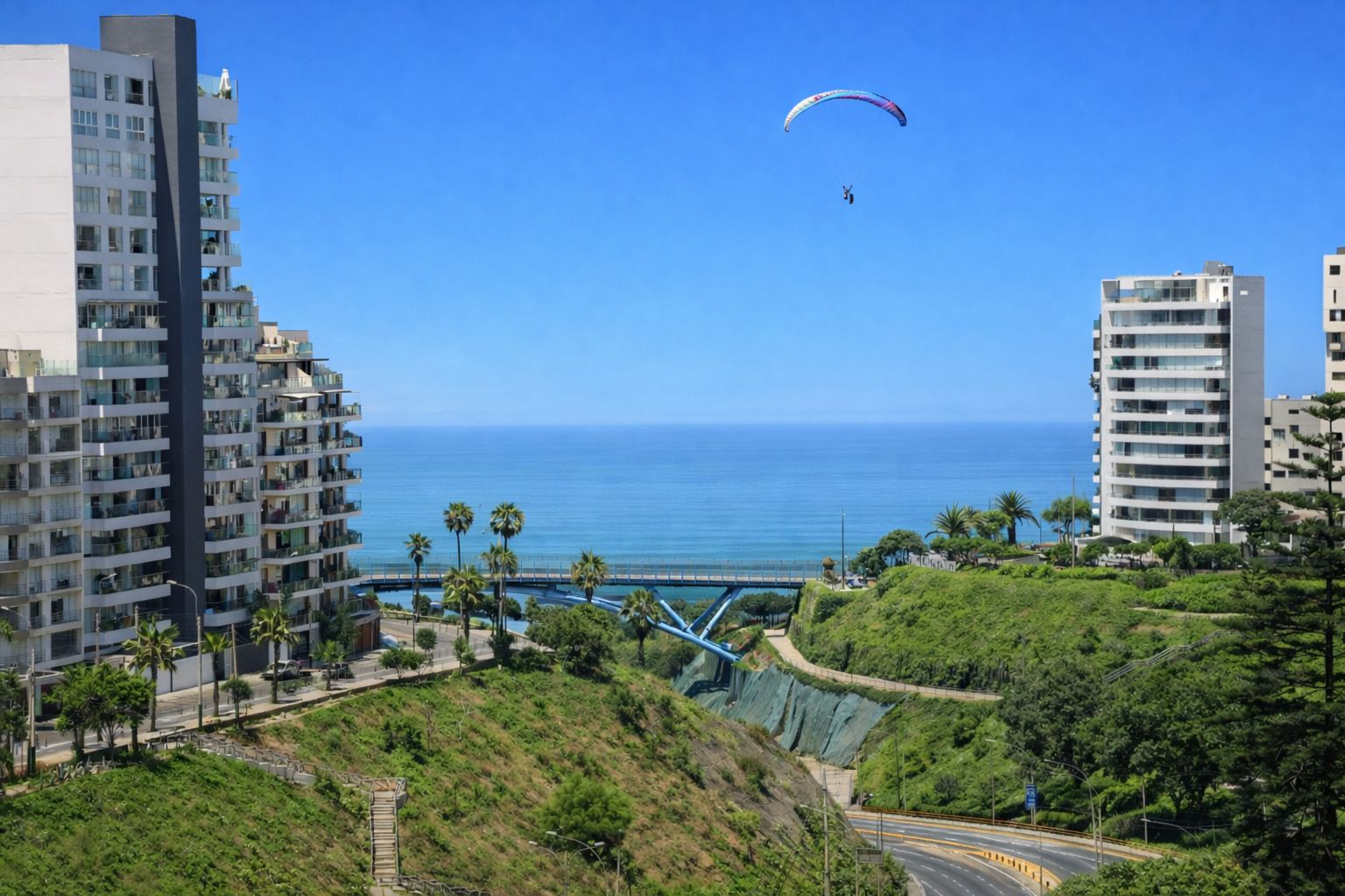 Un paisaje urbano costero con modernos rascacielos, un cielo azul despejado y una persona practicando parapente.