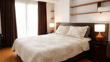 Una habitación de hotel con una cama grande, dos mesitas de noche con lámparas, un cabecero de madera y una ventana con cortinas.