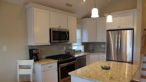 A modern kitchen with white cabinets, stainless steel appliances, granite countertops, and a central island. - Upscale New 3BR 2nd Floor Condo • 2 Blocks to Beach • Walk to Boardwalk & Town (Ocean City)