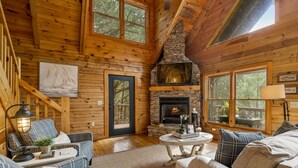 Un intérieur de chalet chaleureux avec des murs en bois, une cheminée en pierre et un coin salon confortable.