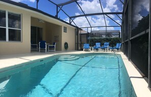 A swimming pool with blue chairs and a covered area.