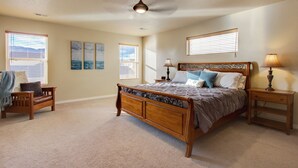 Una camera da letto con un letto in legno, due comodini con lampade, un ventilatore a soffitto e opere d'arte alle pareti.