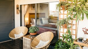 Un espace extérieur accueillant, aménagé avec des fauteuils en osier, une petite table et diverses plantes en pot.