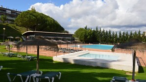Un espace piscine avec des chaises longues, des parasols et un bâtiment en arrière-plan.