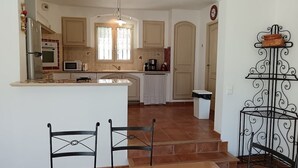A kitchen with a central island, a microwave, a stove, and a sink. There are two chairs and a dining table in the foreground.