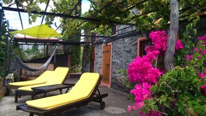 A patio area with two yellow lounge chairs, a hammock, and a yellow umbrella.