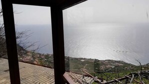 A coastal view from a balcony with a clear view of the sea and a distant village.