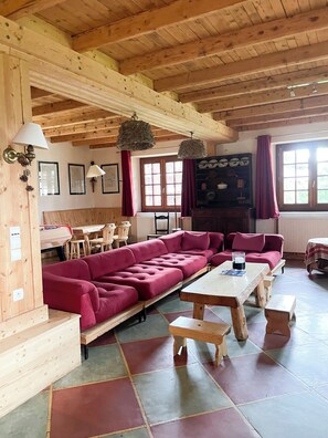 A cozy room with a wooden ceiling, a large sofa, a dining table, and a fireplace. - Traditional chalet in the woods (Crest-Voland)