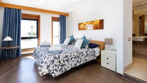 A modern bedroom with a large bed, a bedside table, a nightstand, and a window with curtains. - ViVa Royal (Arona)