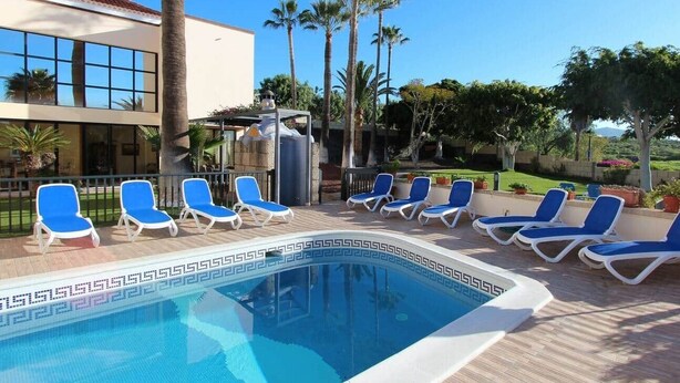 A pool area with blue lounge chairs and a clear blue pool. - ViVa Royal (Arona)