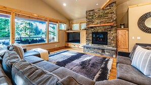 Un salón acogedor con chimenea de piedra, ventanas grandes y un sofá cómodo.
