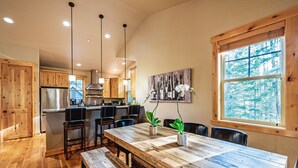 Una cocina amplia con armarios de madera, una isla grande y un comedor con mesa y bancos de madera.