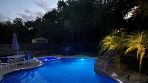 Una piscina de disseny corbat, envoltada per una paret de pedra i palmeres.