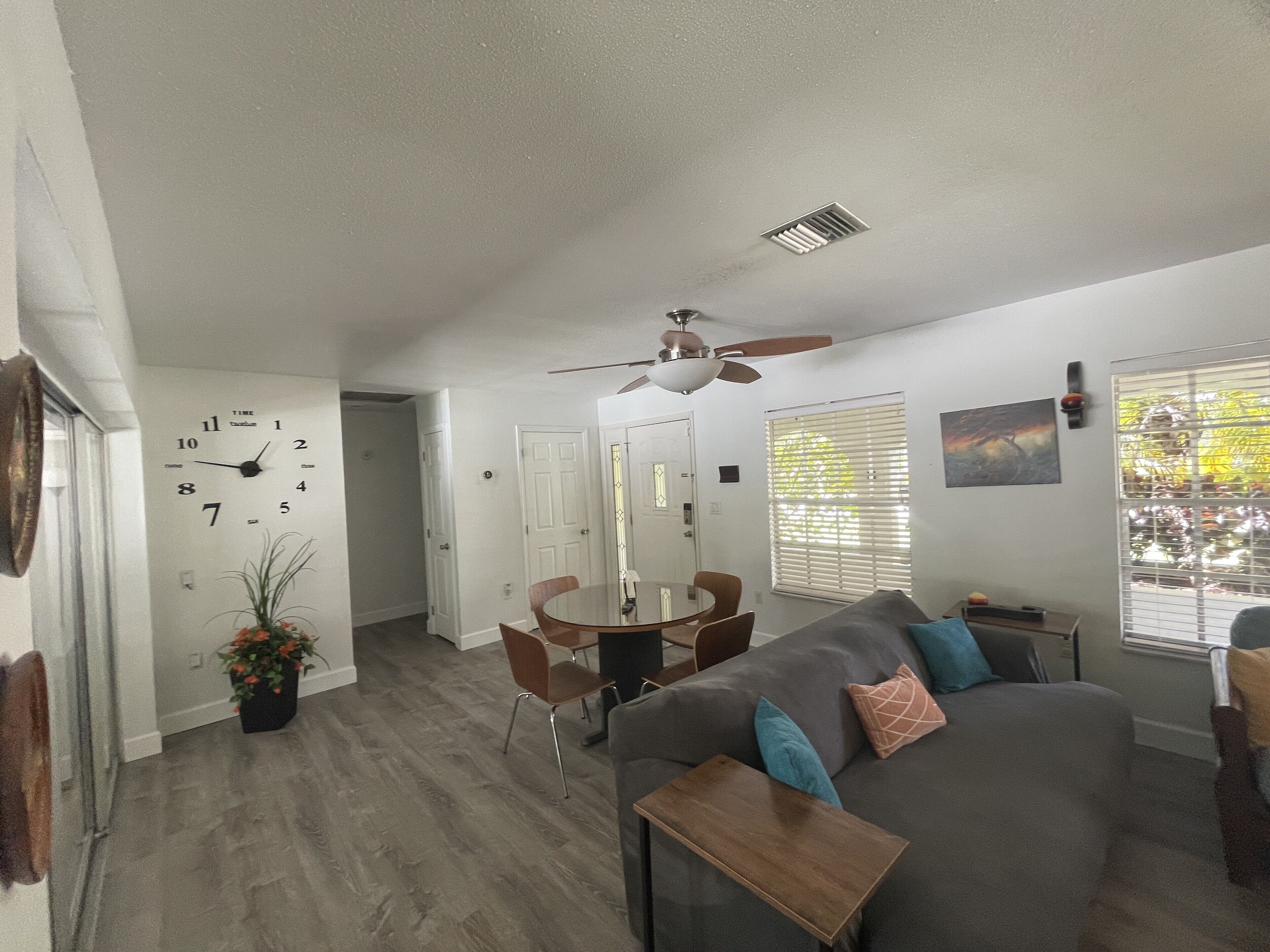 A spacious living room with a gray sofa, a wooden coffee table, and a dining area with a round table and chairs.