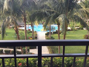 A pool area with palm trees, a pathway leading to the pool, and a well-maintained lawn.