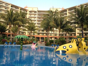 A hotel pool area with a slide and a large yellow play structure. - Beachfront Playa Royale Studio on one of the most prestigious sandy beaches (Nuevo Vallarta)