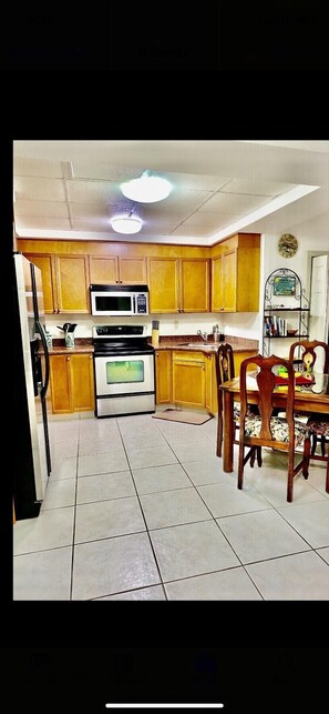 A kitchen with wooden cabinets, a microwave, stove, and a dining table with chairs.