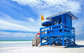 A blue lifeguard tower with a flag on top, located on a beach with clear skies and ocean waves. - 2B/2B 1400sf Siesta Key Townhouse With Parking Garage Across From Public Beach (Siesta Key)