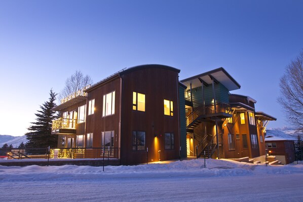 A modern multi-story building with a curved facade, large windows, and a balcony.