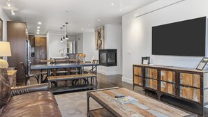 Un salon moderne avec une table basse en bois, un canapé en cuir et un coin repas comprenant une table et des bancs en bois.