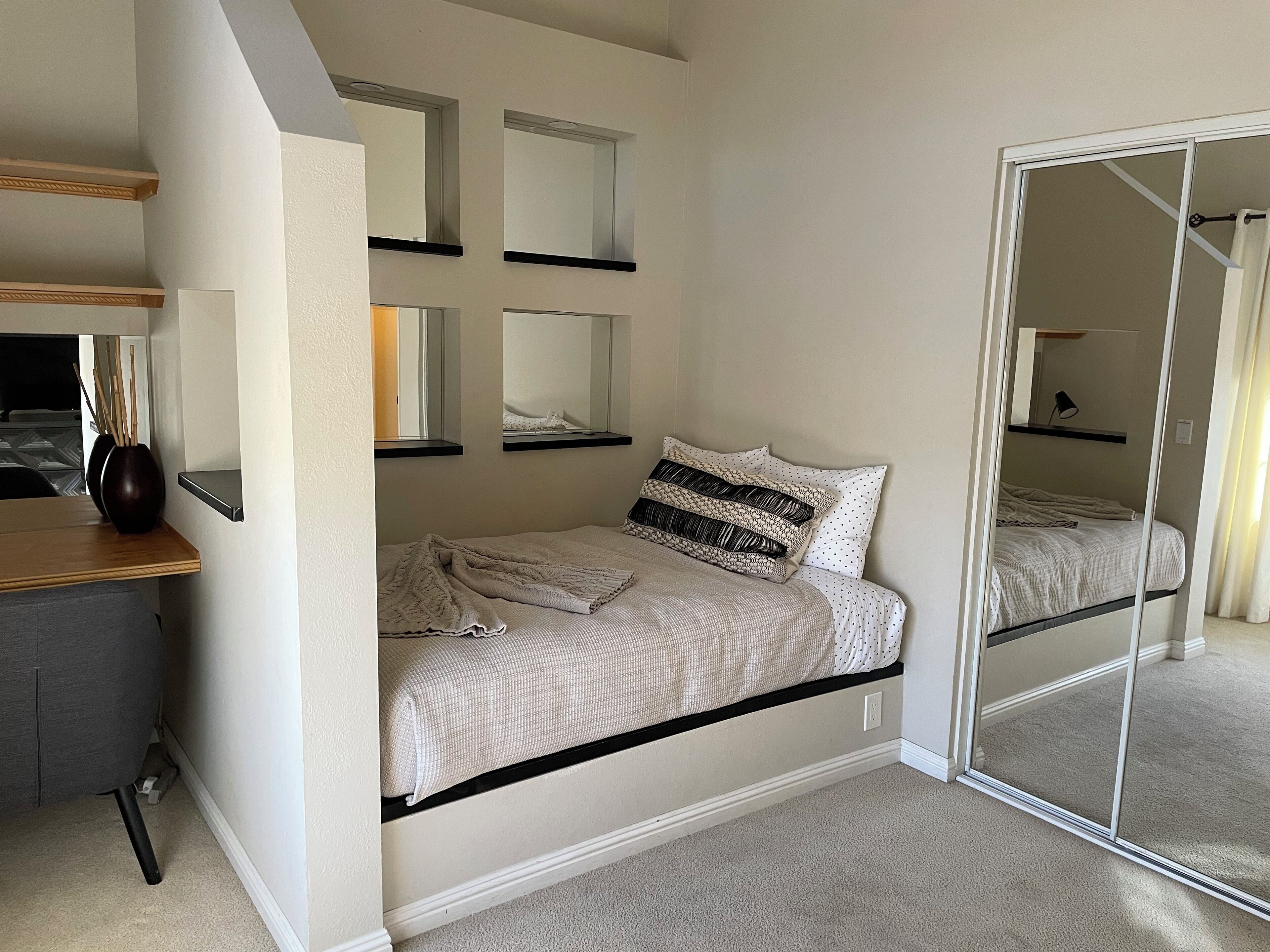 Un dormitorio con cama, escritorio y espejo.