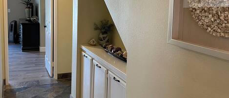 A hallway with a stone tile floor, a white door, and a wall-mounted light fixture.